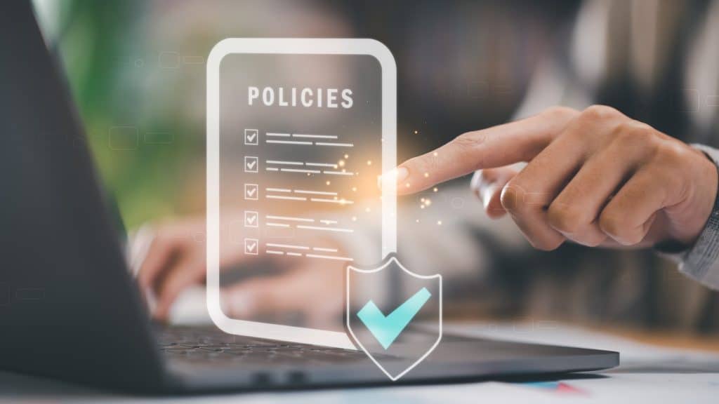 Someone on a laptop looking at policies and pointing to each policy to tick them off.