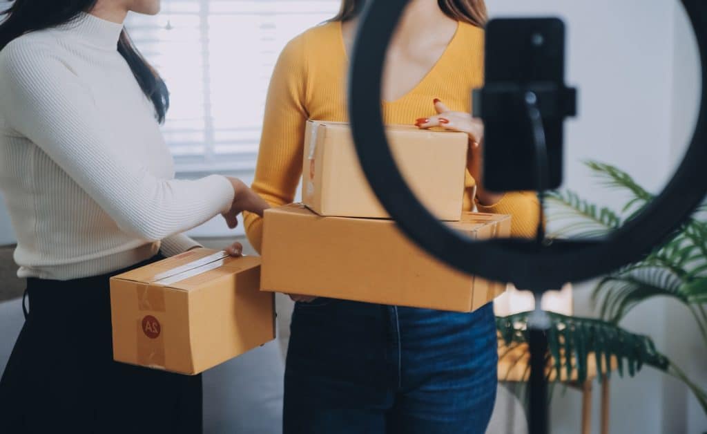 Two women who are live on TikTok Shop, showing the boxes they're going to send out for TikTok Shop shipping