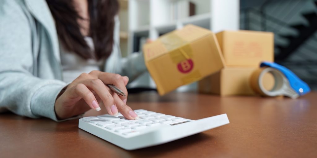 A business owner working out shipping costs to represent ‘Calculating Shipping Costs for an Online Business’.